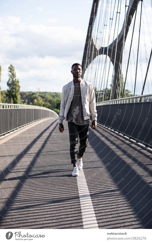 Young Black Man Walking Confidently on Bridge man black african ethnicity walk real person one person one man only fashionable city life bridge front view