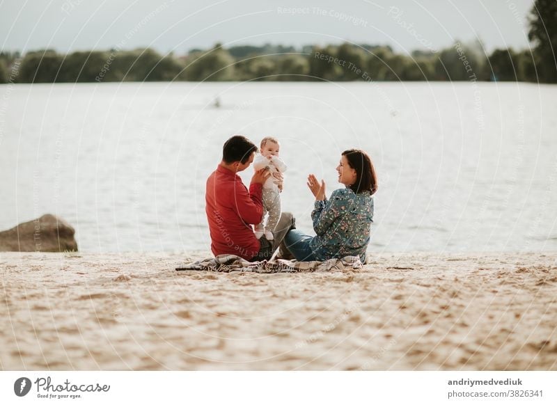 happy family resting by the lake. family with a small child nature parent mother daughter summer love together holiday happiness fun girl father smiling cute