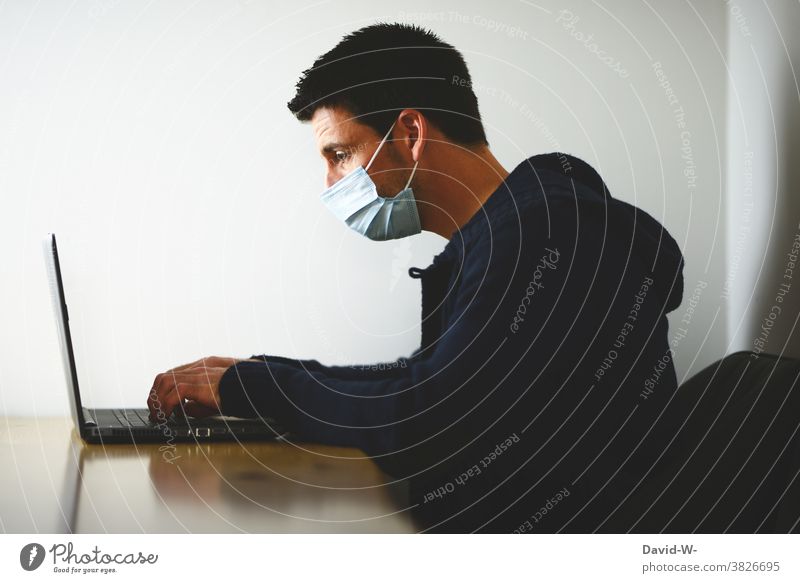 Quarantine and home office - man works with breathing mask on laptop corona Respirator mask Mask by oneself Lonely Corona virus pandemic