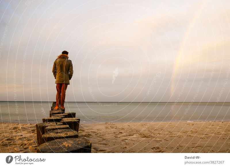 Man stands on poles that go into the sea and admires the rainbow Rainbow North Sea Far-off places coast tranquillity Beach Vacation & Travel Water Sky Island