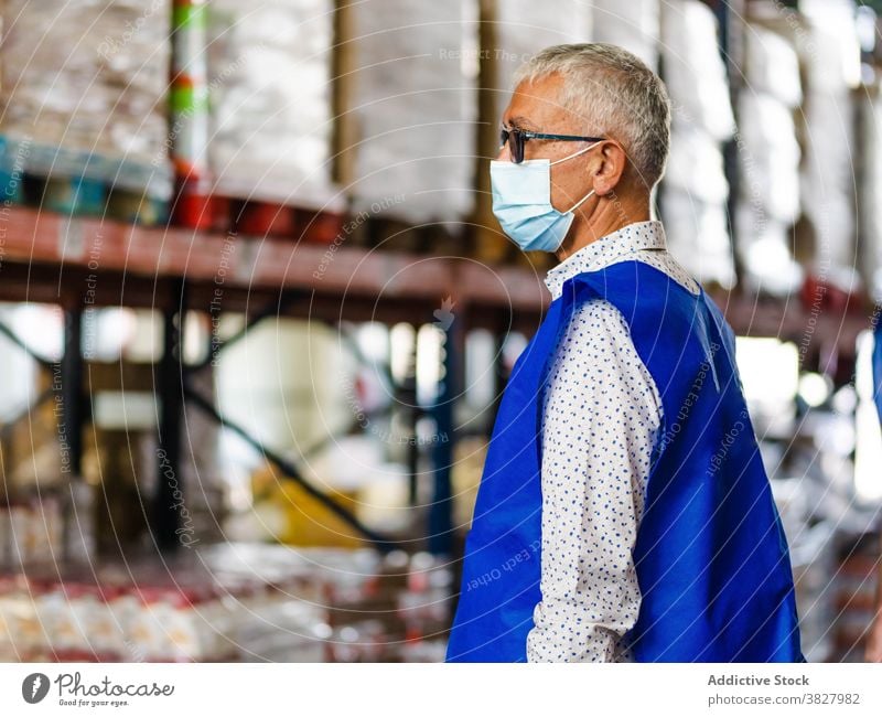 Calm male worker standing in warehouse man professional at work industry uniform calm focus storehouse industrial coronavirus adult vest serious employee