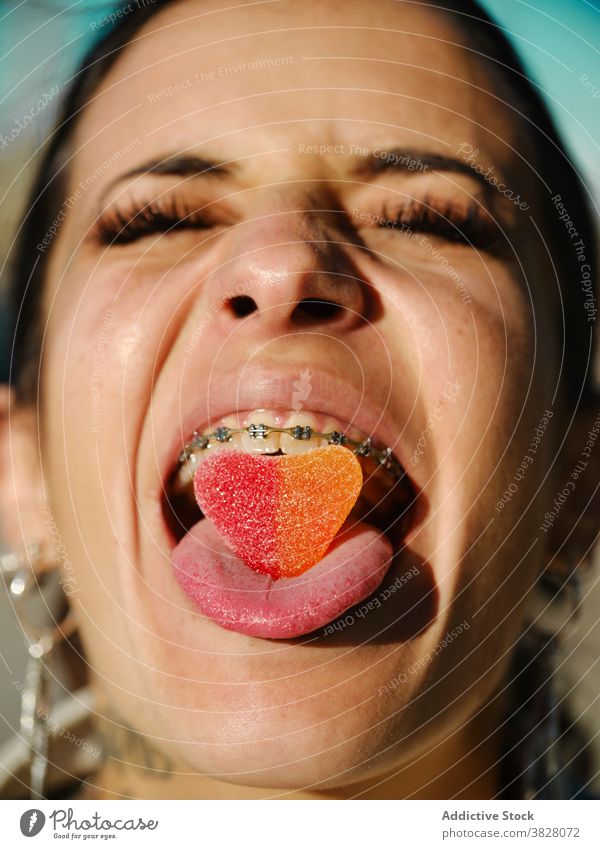 Expressive woman with gummy candy in mouth eccentric tongue out stick out sweet treat expressive brace female dessert sugar pleasure yummy eyes closed delicious