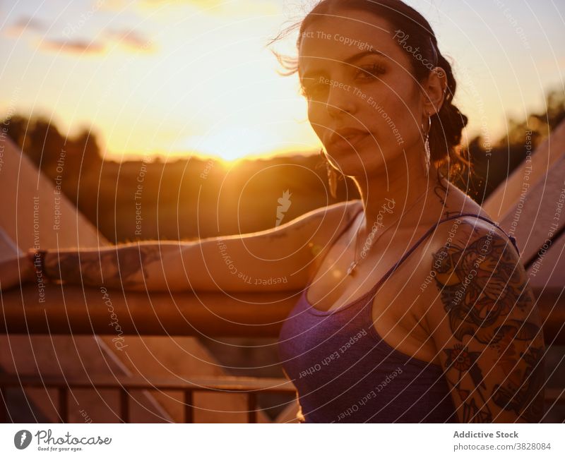 Stylish woman in tattoos standing in city style trendy bridge metal sunset summer relax rest enjoy young urban freedom delight glad evening twilight cool