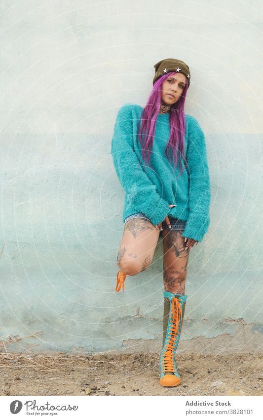 Stylish tattooed woman on street style informal pink hair appearance eccentric fancy trendy female shabby building urban area outfit relax town cool millennial