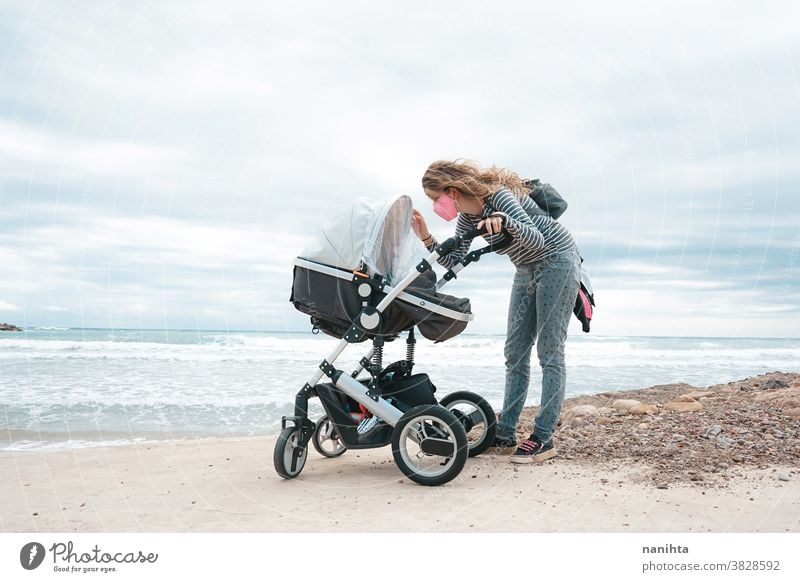 Young mom walking with her baby during covid pandemic covid-19 coronavirus motherhood family holidays mask face mask daughter beach outdoors sea shore autumn