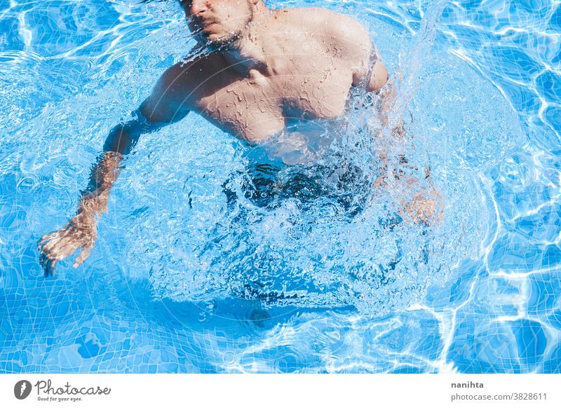 Young man enyoing the day at the swimming pool playful summer water attractive cool fresh holidays fun funny sport sportive swim trunks life lifestyle enjoy