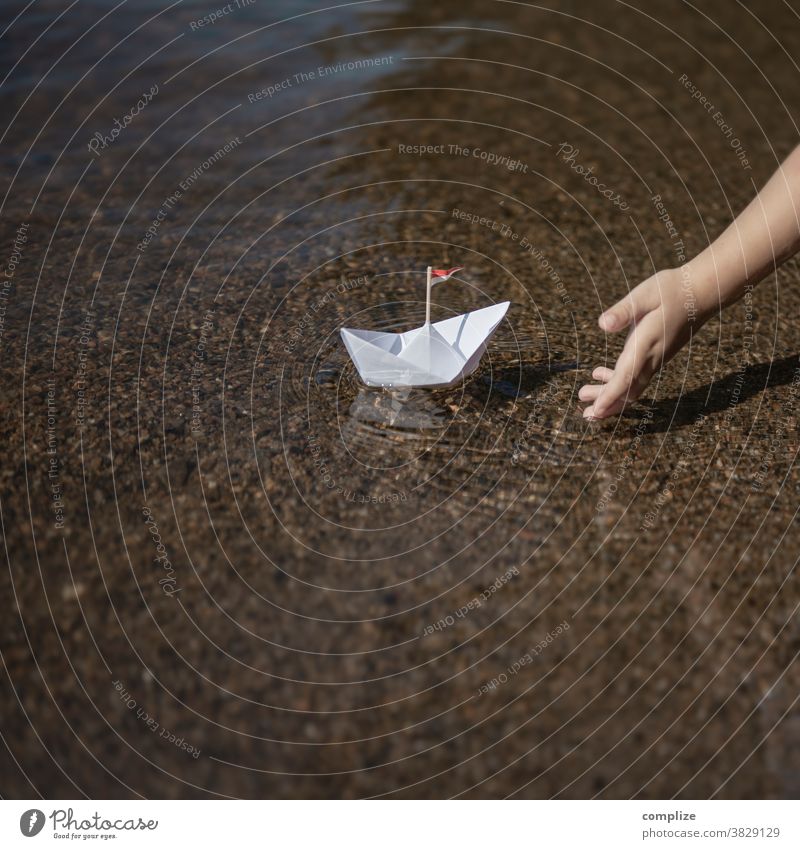 Little child puts a paper ship in the water Colour photo Resume Paper boat Beach Lakeside Future 3 - 8 years coast Waves Child Infancy Hand Logistics
