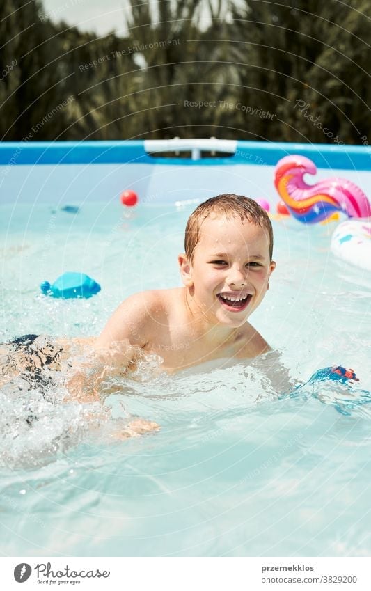 Portrait of happy smiling boy playing in a pool having fun on a summer sunny day authentic backyard childhood children family garden happiness joy kid laughing