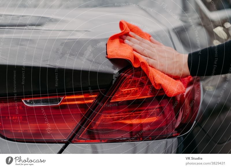 Cleaning auto concept. Mans hand wiping car hood with microfiber cloth. Unrecognizable man polishes vehicle. Detailing or valeting arm automobile care clean
