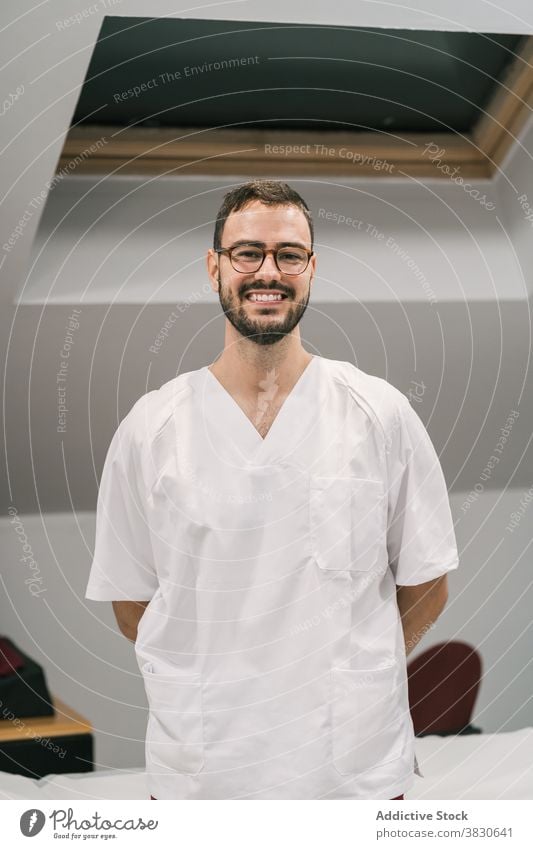 Cheerful doctor in uniform in medical room white gown man cheerful staff clinic office male medicine job modern specialist smile treat professional positive