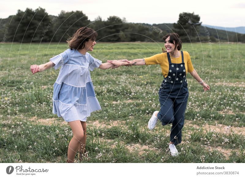 Positive women running through meadow happy excited carefree having fun summertime slender nature cheerful toothy smile harmony field friendship free time