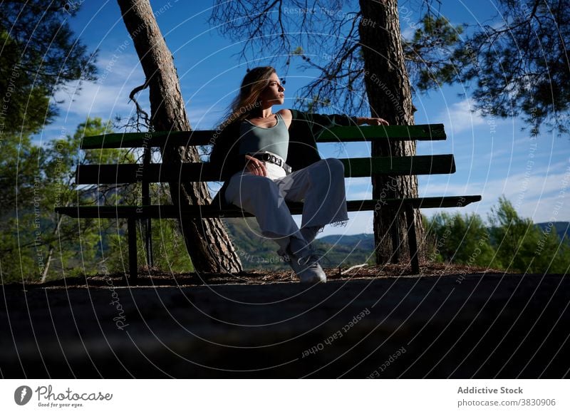 Relaxed woman resting on bench in forest contemplate relax sunlight nature woods calm peaceful pensive dream thoughtful young female tranquil lifestyle enjoy