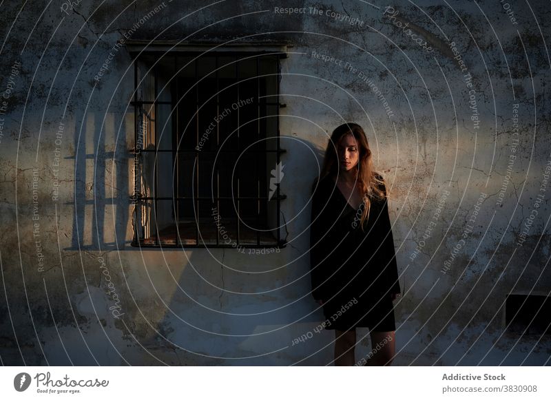 Woman in black dress standing near weathered building woman shabby wall aged grunge alone gloomy depression young female exterior ancient house calm tranquil