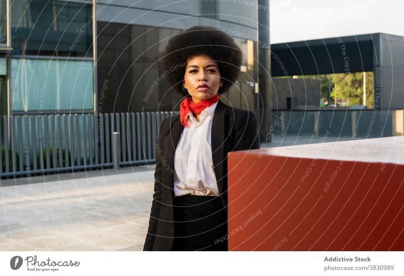 Confident black woman in formal outfit standing near colorful wall concentrate employee elegant occupation worker respectable style confident female serious