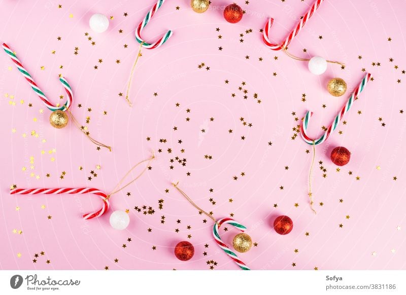 Christmas frame on pink with confetti, candy canes christmas new year background december flat lay color trendy golden star sparkling glitter ornament give