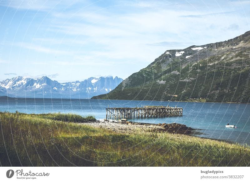 Fjord landscape in Norway with a jetty leading into the water, the view to the fjord and snow-covered mountains in the background. fjord view Landscape Mountain