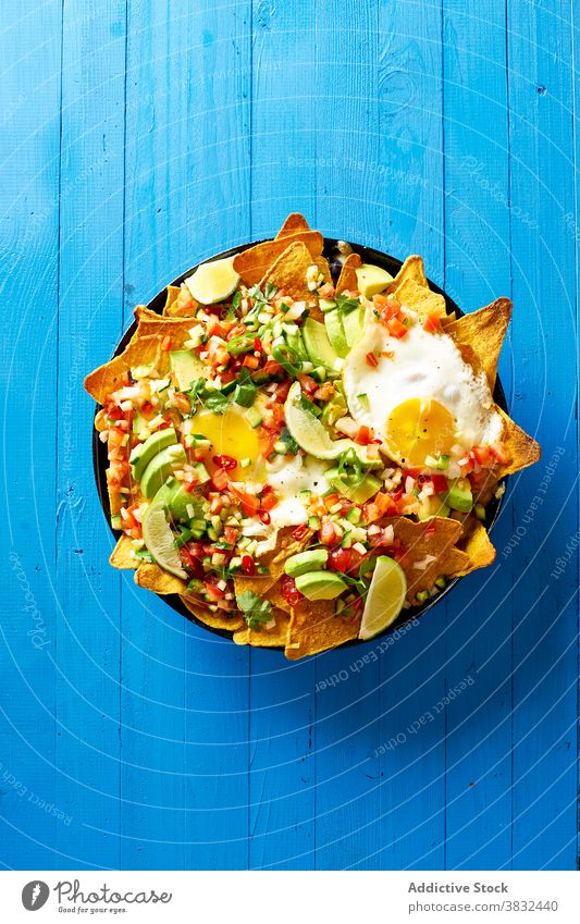 Chilaquiles dish with avocado food chilaquiles mexican tortilla top view breakfast overhead black beans nachos cilantro sauce fried meal chips fresh salsa
