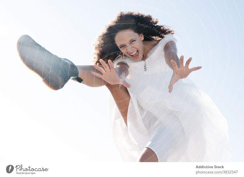 Joyful happy woman jumping and shouting rebel joyful freedom cool ethnic laugh stretch white dress summer scream positive young cheerful fun modern healthy