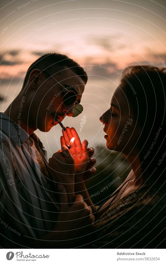 Couple smoking cigarettes at seaside smoke couple relax lighter together girlfriend boyfriend sunset seashore love vacation romantic calm evening nicotine habit