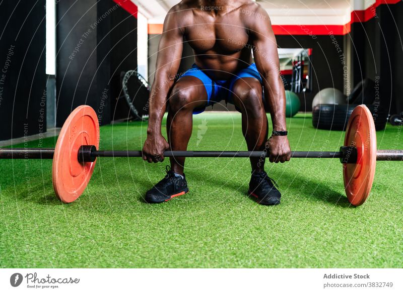 Black athletic man lifting barbell in gym weightlifting heavy sportsman muscular torso bodybuilder strong ethnic black african american modern center athlete