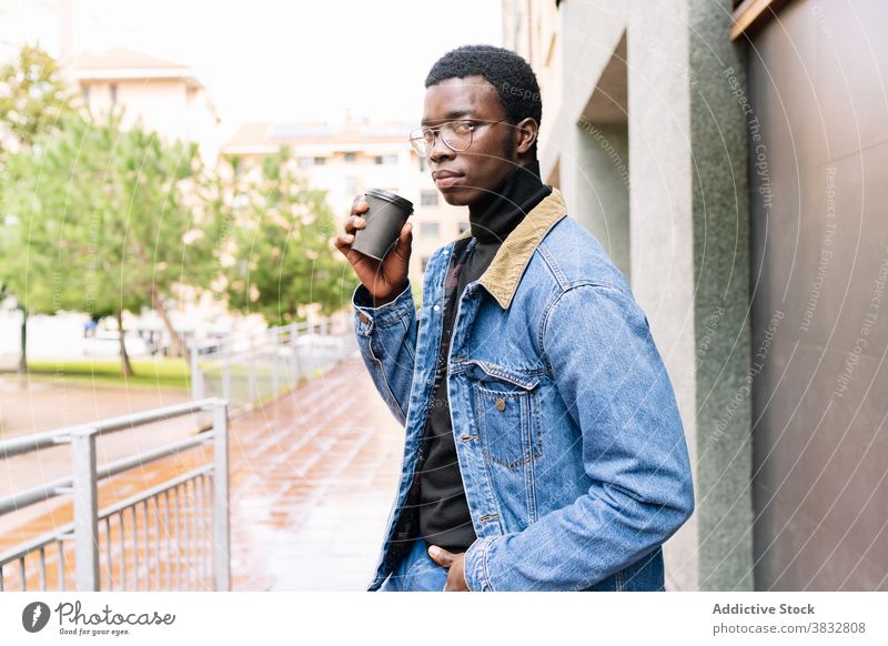 Trendy black man with takeaway coffee in city to go style denim outfit trendy drink male ethnic african american cool stool street delicious modern sit guy