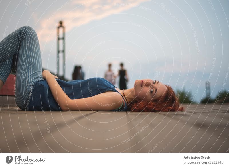 Relaxed woman lying on city embankment relax rest red hair calm sensual evening serene young redhead female millennial traveler saint petersburg russia