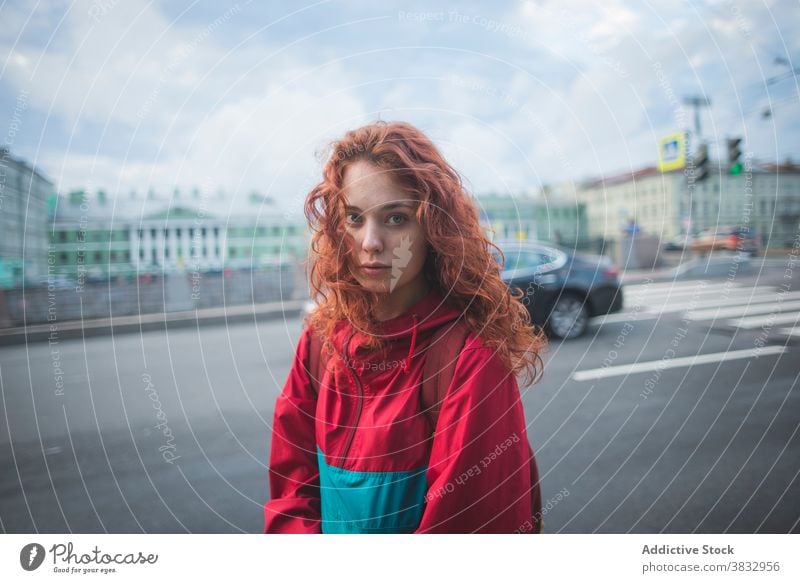 Young red haired woman standing near road in city redhead urban young wind serious millennial street curly hair long hair female saint petersburg russia travel