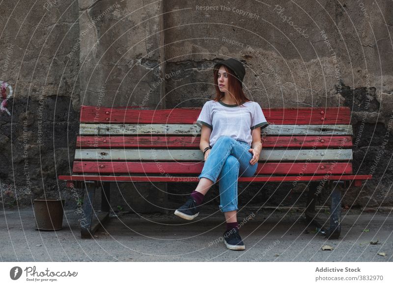 Trendy female teenager sitting on bench woman hipster trendy hat millennial urban style student informal casual young fashion lifestyle alone lonely pensive