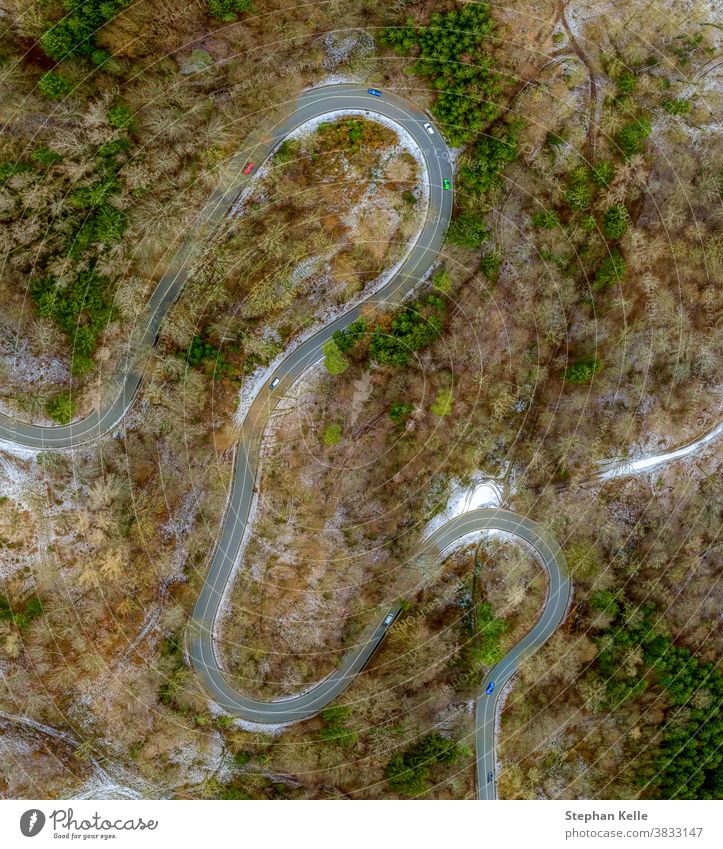 Winding road in the transition from autumn to winter, snow at a germany roa, filmed straight from above. background car tree nature eyecatcher ice view aerial