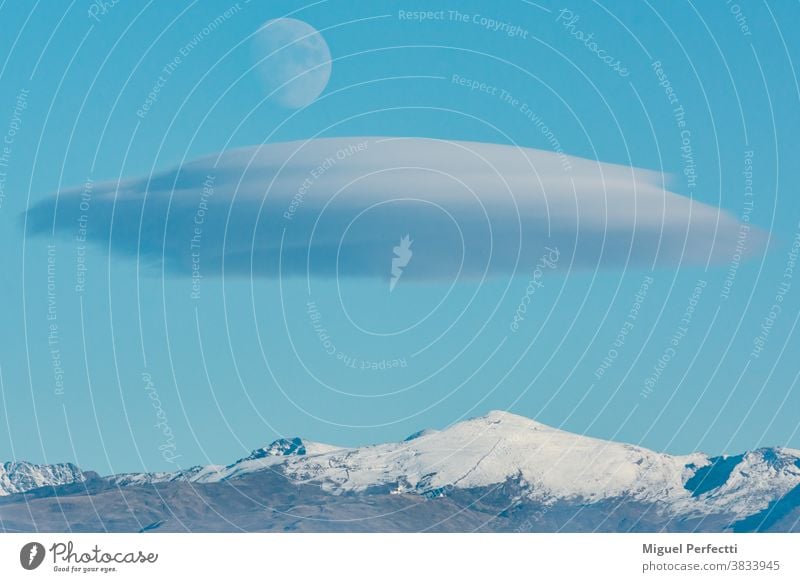 Landscape of Sierra Nevada in Granada with a lenticular cloud and the moon over it. Veleta peak mountain landscape tourism snow skiing Andalucia mountaineering
