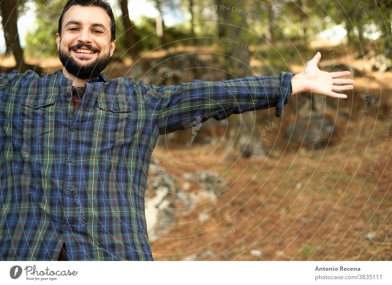 Man with beard and plaid shirt of aesthetic lumberjack spreads his arms in the middle of nature with joy man freedom forest woodcutter bearded emotion happy