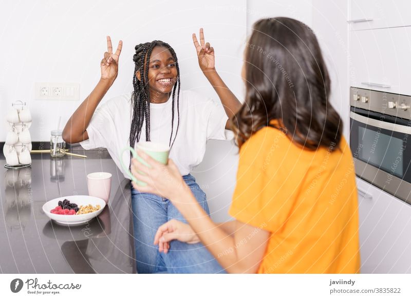 Two friends having a healthy snack while chatting at home women food eating multiethnic multiracial appetizer house vegetarian student black afro lifestyle girl