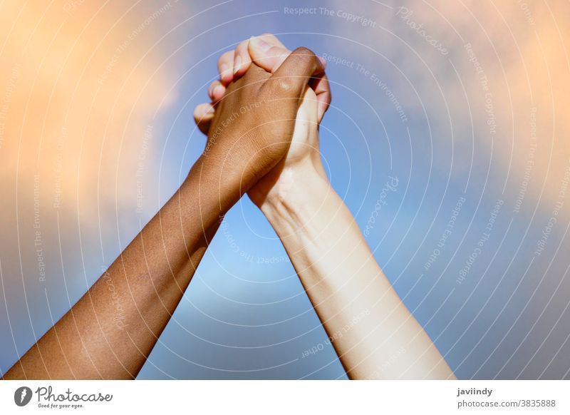 Multiethnic women's hands together against cloudy sky. multiethnic multiracial people black life matters african friendship caucasian blue diversity skin