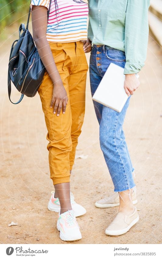 Two unrecognizable multiethnic girls posing together with colorful casual clothing woman friend tablet digital female young lifestyle urban beautiful device