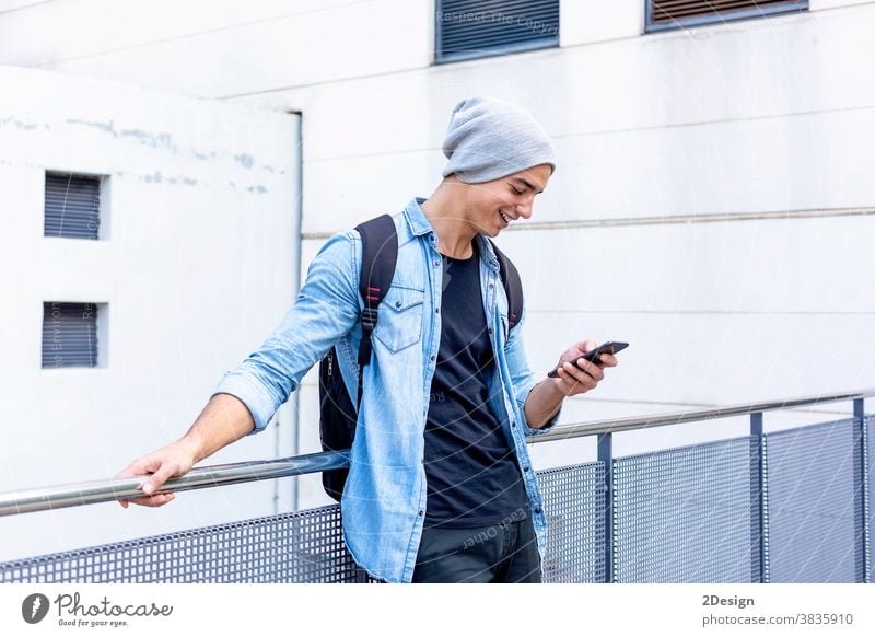 Urban stylish young man standing by the wall using cellphone smartphone talking calling guy mobile male technology city lifestyle urban communication
