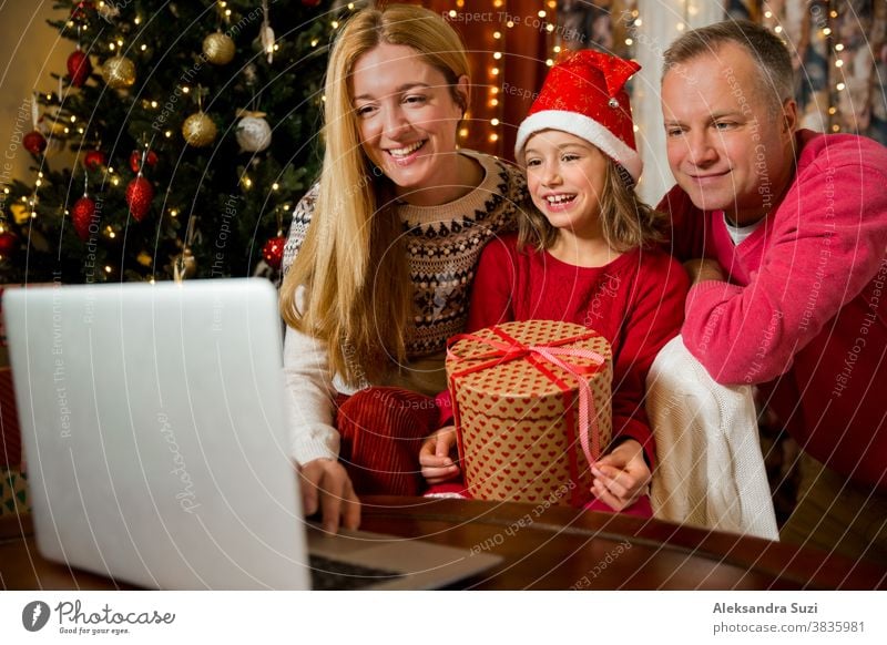 A happy couple with a child is celebrating Christmas with their friends on video call using webcam. Family greeting their relatives on Christmas eve online. New normal