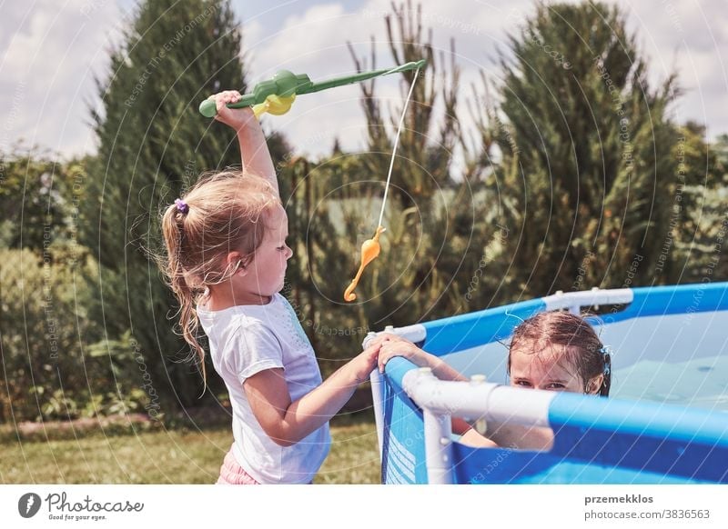 Children playing with fishing rod toy in a pool in a home garden - a  Royalty Free Stock Photo from Photocase