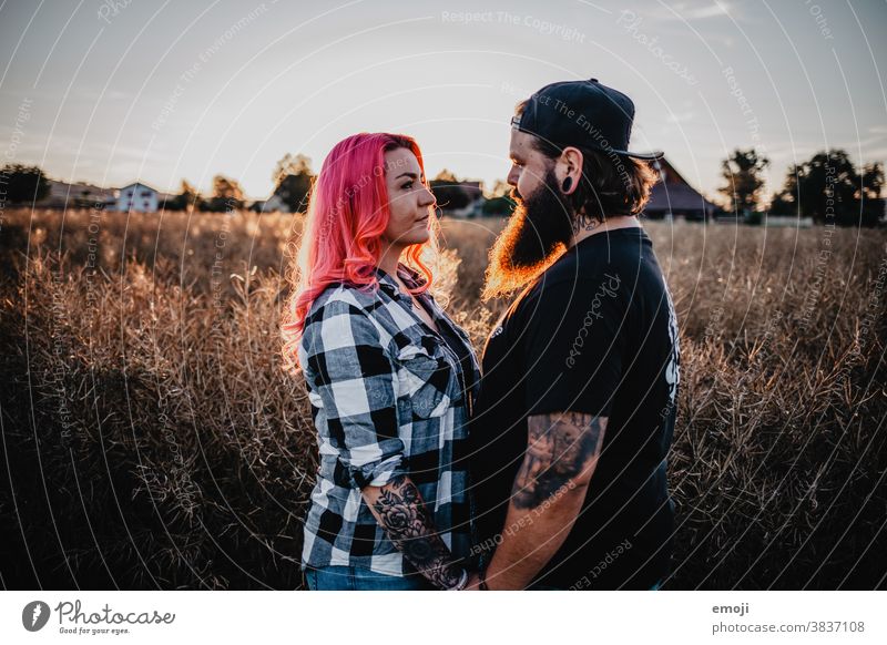 young couple with tattoos and pink hair teen Couple Love In love Sunset out Field Tattoo Hip & trendy Hipster Man Woman eye contact Profile Opposite