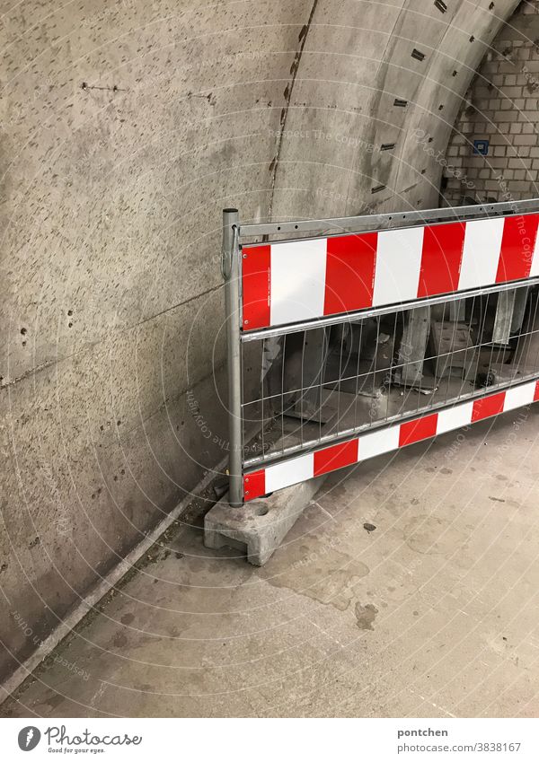 A red and white striped barrier in front of a concrete wall.  Safety, Warning, Prohibition cordon Grating Reddish white interdiction Passage Underground Barrier