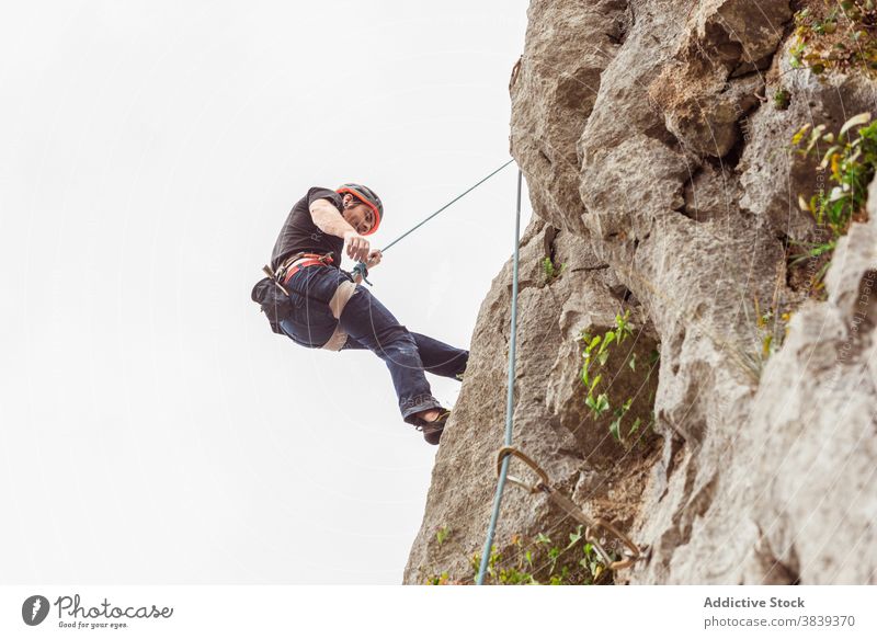 Male climber ascending on sheer cliff in summer man alpinist mountain practice climbing active mountaineering male risk travel extreme freedom adrenalin