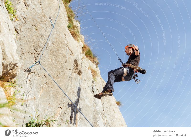Male climber ascending on sheer cliff in summer man alpinist mountain practice climbing active mountaineering male risk travel extreme freedom adrenalin