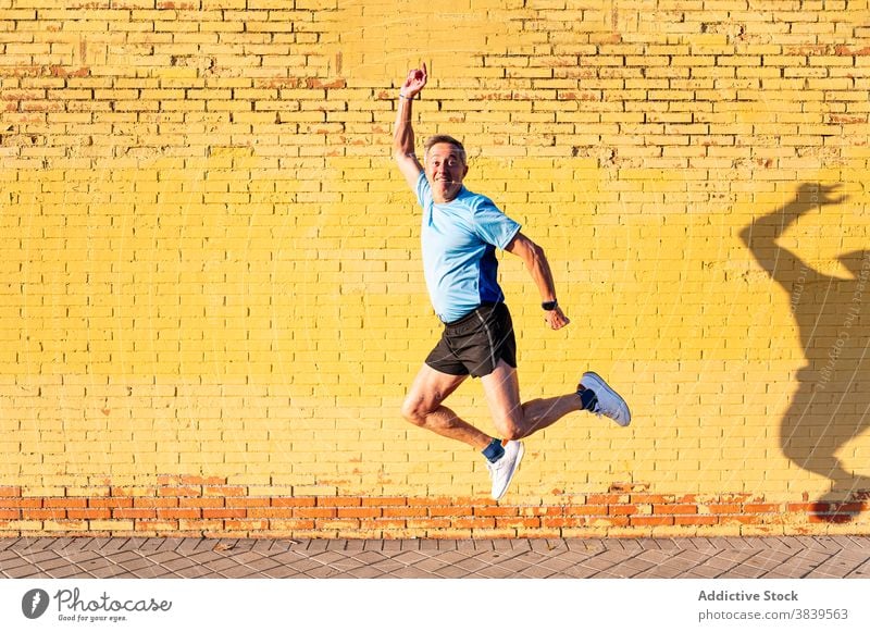 Senior retired man athlete jumping on yellow background 60 58 rest rythm health care fitness high-blood-pressure training cardiac old neck rate caucasian check