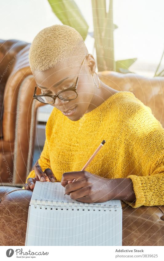 Thoughtful ethnic woman taking notes in notepad idea write take note thoughtful think pensive memo terrace female black african american notebook armchair work