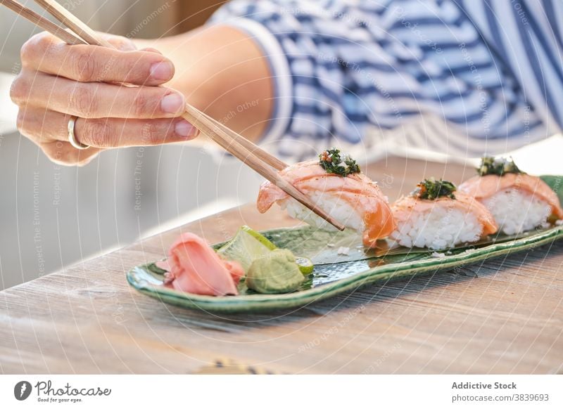 Anonymous person eating tasty sushi Nigiri on plate in cafe nigiri rice salmon asian food restaurant seafood oriental tradition fish delicious gourmet dish meal