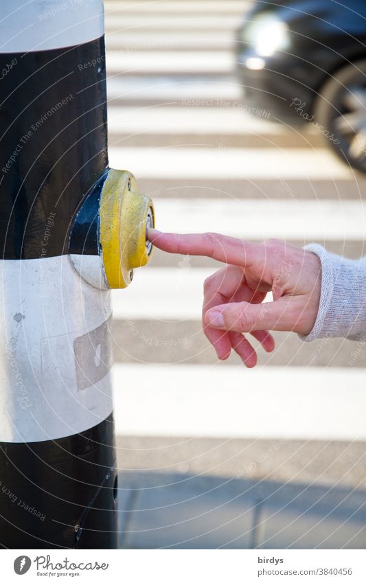 Pedestrian presses contact button, request button at a pedestrian traffic light. female hand presses the request button, crosswalk with passing car Transport