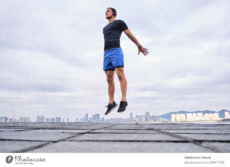 Active sportsman jumping during training in city runner warm up active cardio leap street male workout athlete fitness energy body exercise healthy urban