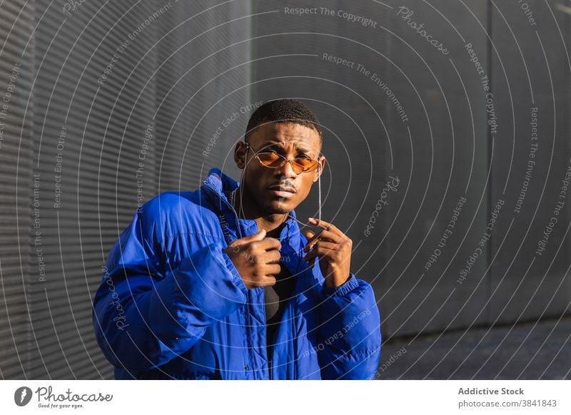 Stylish black man in sunglasses on street style orange trendy outfit determine cool urban male ethnic metal wall african american confident modern warm jacket