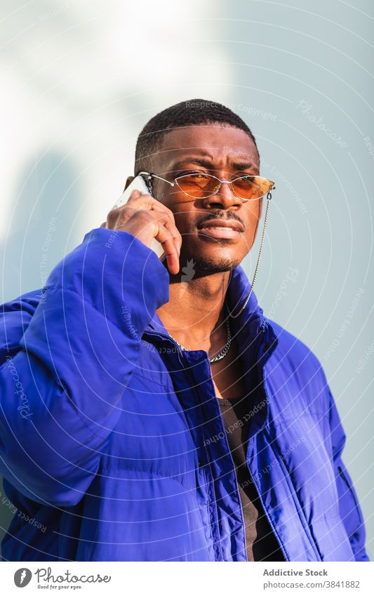 Trendy black man on smartphone in city style cool hipster determine using trendy male ethnic african american warm blue jacket street sunny modern handsome