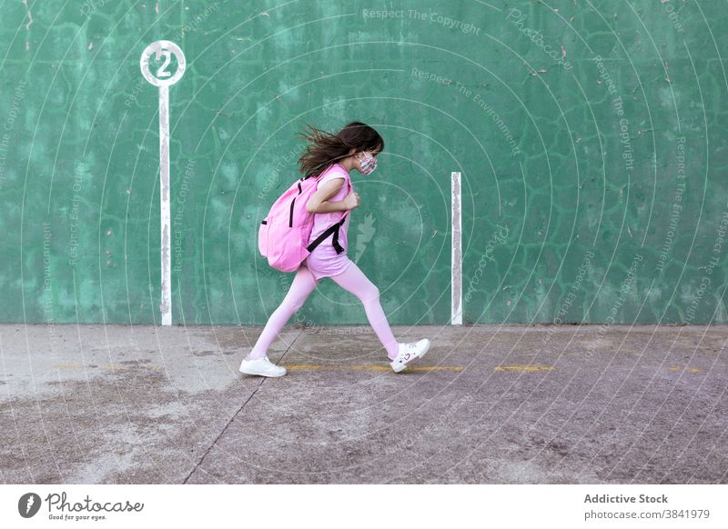 Child in mask and with backpack walking along street schoolgirl coronavirus epidemic kid rucksack town urban child city schoolkid schoolchild protect new normal