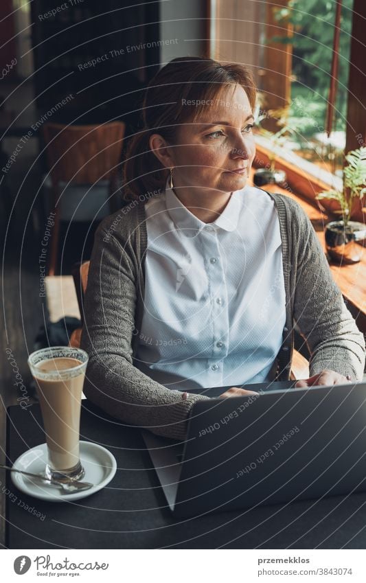 Businesswoman working remotely on her laptop managing her work sitting in a cafe business caucasian computer connection desk entrepreneur female indoors